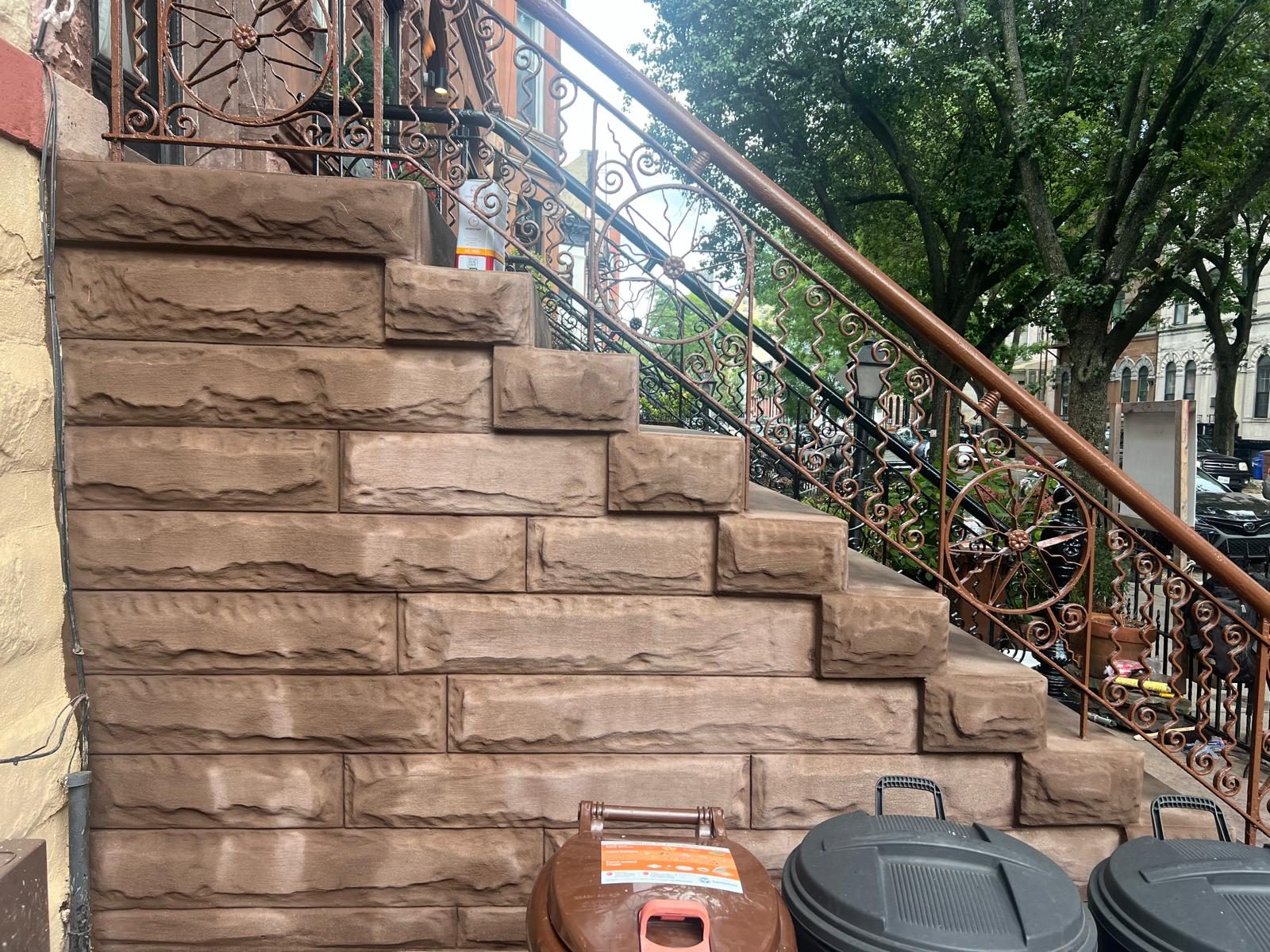Restored brownstone stoop with carved balustrades, urn-topped newel posts, and ornamental iron railing